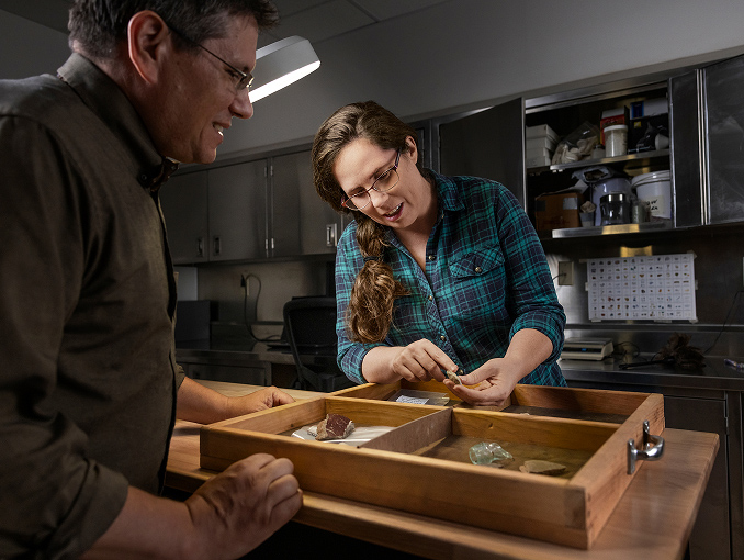 Two archaeologists inspecting small pieces of rock in a lab
