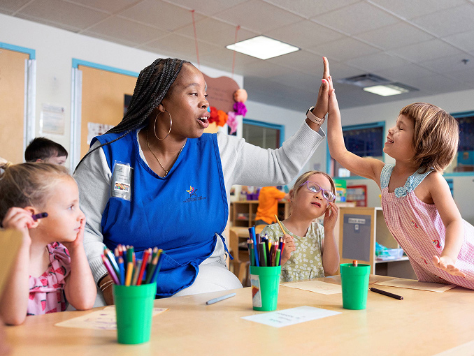 A female teacher high-fiving one of her students in her classroom
