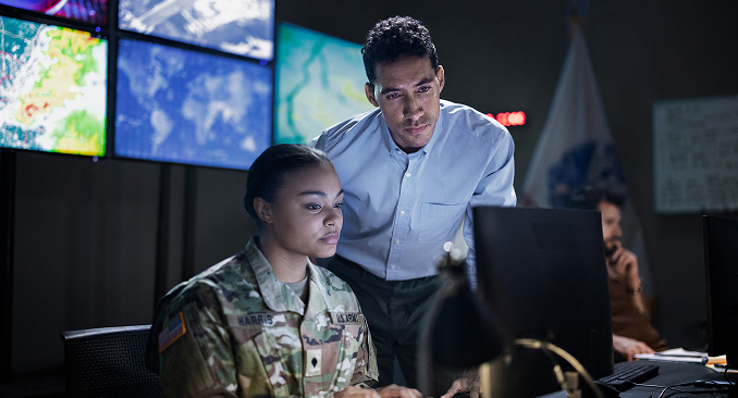 An Army Civilian working with a Soldier in a cyber command center